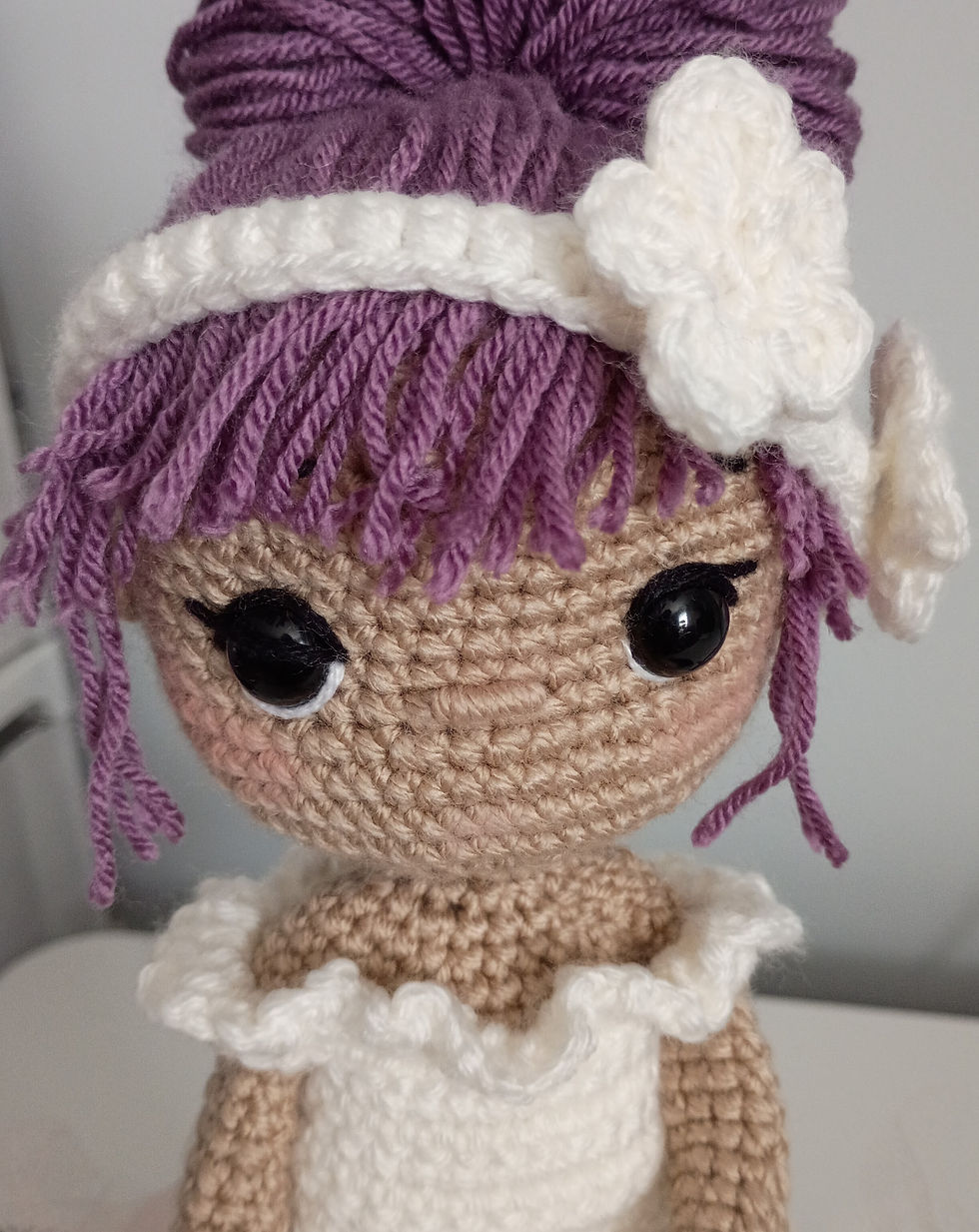 Close-up view of a colorful personalized crochet doll sitting on a wooden shelf