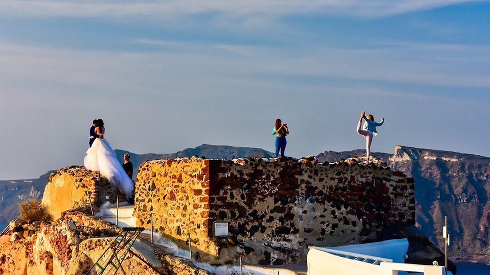 Bad tourists perched on the wall of an ancient castle in Santorini, Greece