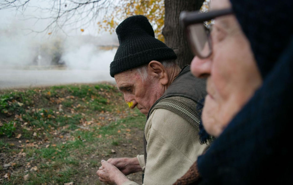 Portrait of an elderly Romanian couple sitting on a bench.