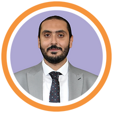 Ein Mann, CAIO Bassam Khalifa, mit dunklem, akkurat gestutztem Vollbart, trägt einen hellgrauen Anzug und ein weißes Hemd. Er steht vor einem schlichten hellen lila Hintergrund und posiert für ein professionelles Porträt. Er trägt eine schwarze Krawatte mit kleinen roten und blauen Tupfen. Er hat einen ruhigen, zuversichtlichen Gesichtsausdruck und lächelt leicht.