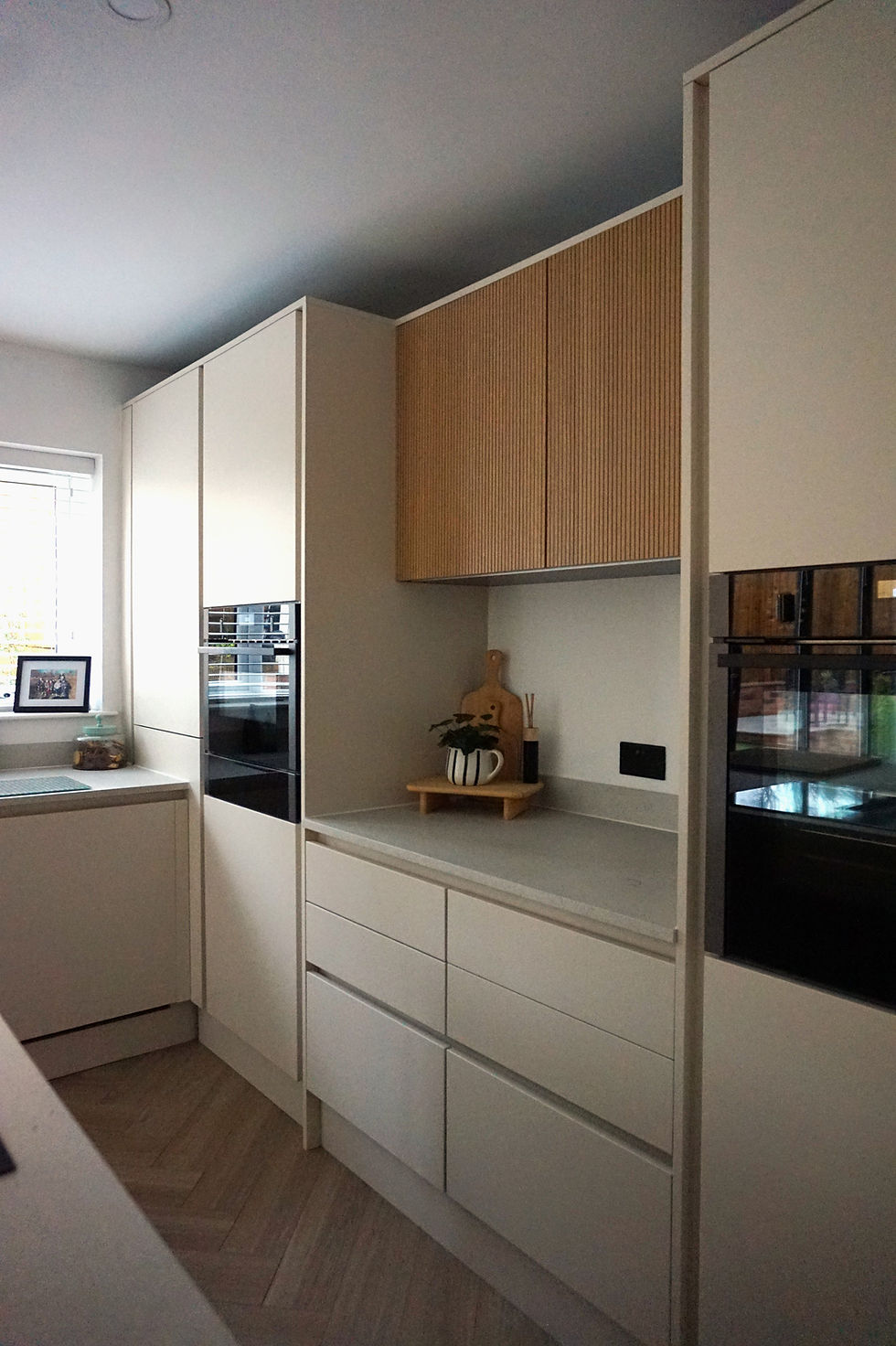 Light neutral spray finished kitchen cabinets with integrated ovens and handleless drawers in Merthyr Tydfil renovation