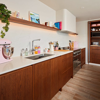 Bespoke kitchen in Cardiff featuring walnut-stained oak cabinetry with clear coat finish and Farrow & Ball Ammonite spray-finished units, handcrafted by Adam Farmer Bespoke Fitted Furniture and professionally sprayed by Bespoke Spray Cardiff, showcasing luxury custom joinery, modern design, seamless cabinetry lines, premium finishes and contemporary kitchen styling in South Wales