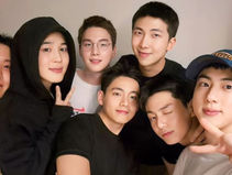 BTS members take a cozy group selfie, showcasing their close bond and cheerful expressions.