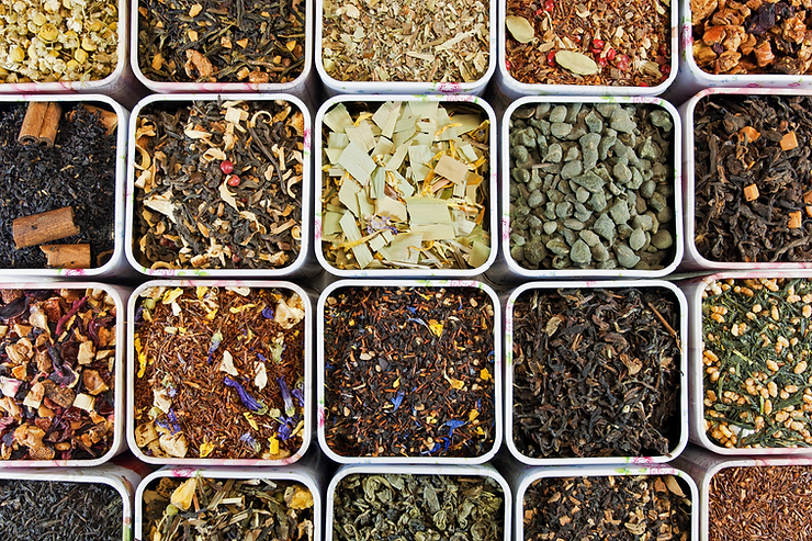 Various types of loose-leaf tea displayed in small bowls, showcasing different colors and textures.