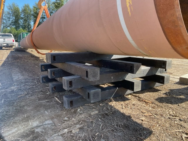 Skid Tech interlocking skid system supporting a pipeline, showcasing the durable recycled HDPE material and stable pile structure.