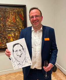 Guest smiling while holding up his caricature at the Courtauld Gallery