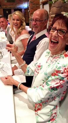 Wedding guests laughing over a caricature at the top table