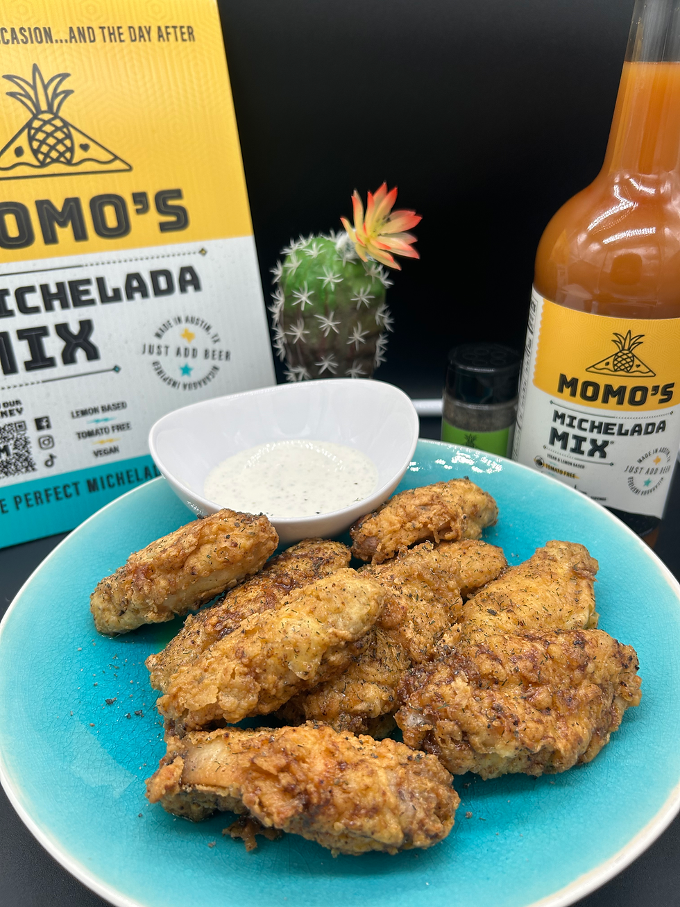 Golden Fried Chicken Wings on a blue plate with a side of ranch dressing, sitting next to a bottle of Momo's michelada mix.