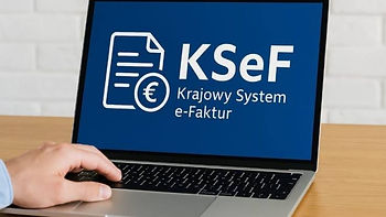 Ноутбук с логотипом KSeF Krajowy System e-Faktur на синем экране; рука у тачпада, офисный стол.