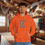 Thumbnail: Man wearing orange hoodie saying "Sorry I wasn't listening I was thinking about fishing". Men's Comfort Hoodie Wolf's Den Clothing