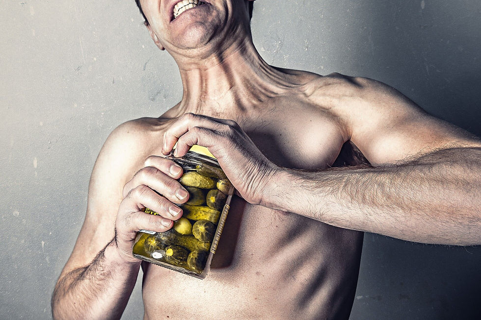skinny man struggling to open a jar of pickles