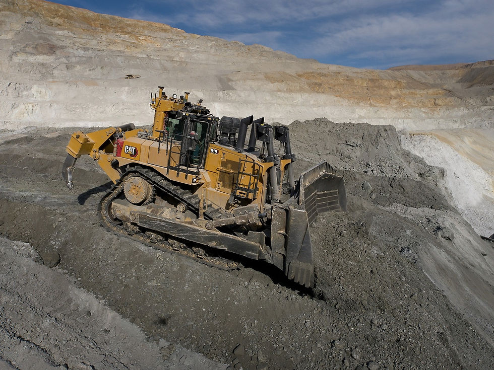A yellow bulldozer operates on a steep dirt slope in a quarry under a partly cloudy sky. The setting is rugged and industrial in Miami, FL.