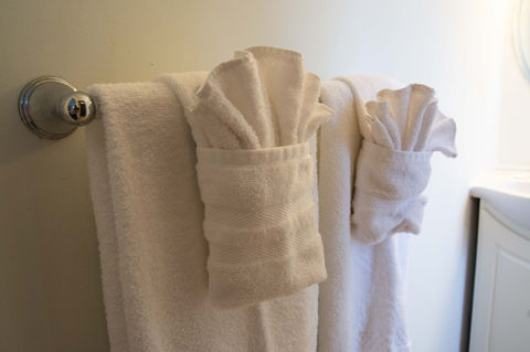Neatly folded towels hang over a towel bar in a bathroom.