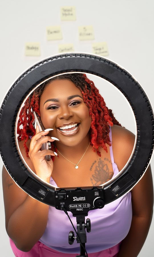 Jessica Le'Gail smiling through a ring light on her phone