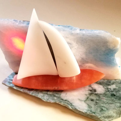 I tried to bring some motion to the ocean, a direction of the breeze to force a lean and tilt to the sailboat. The hull is red alabaster. The sails are pure white Carrara marble statuario. The sea is a green marble conglomerate with a sky of Persian pink onyx. I painted the back of the translucent pink onyx with a blue background which gave it a cool effect. It is illuminated with LEDs.
12"W x 9" T x 6" D