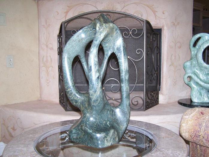 Green abstract sculpture on a table in front of a fireplace. Various Sculptures