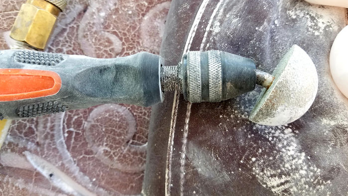 Power drill grinding a stone with Tools of the Trade on a work surface