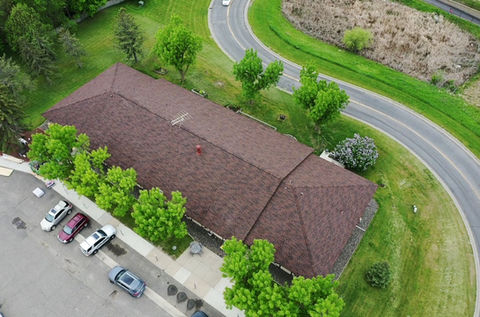 Aerial view of commercial roofing project in Minnesota completed by 1st Call Construction & Exteriors, showing newly installed shingle roof on commercial building.