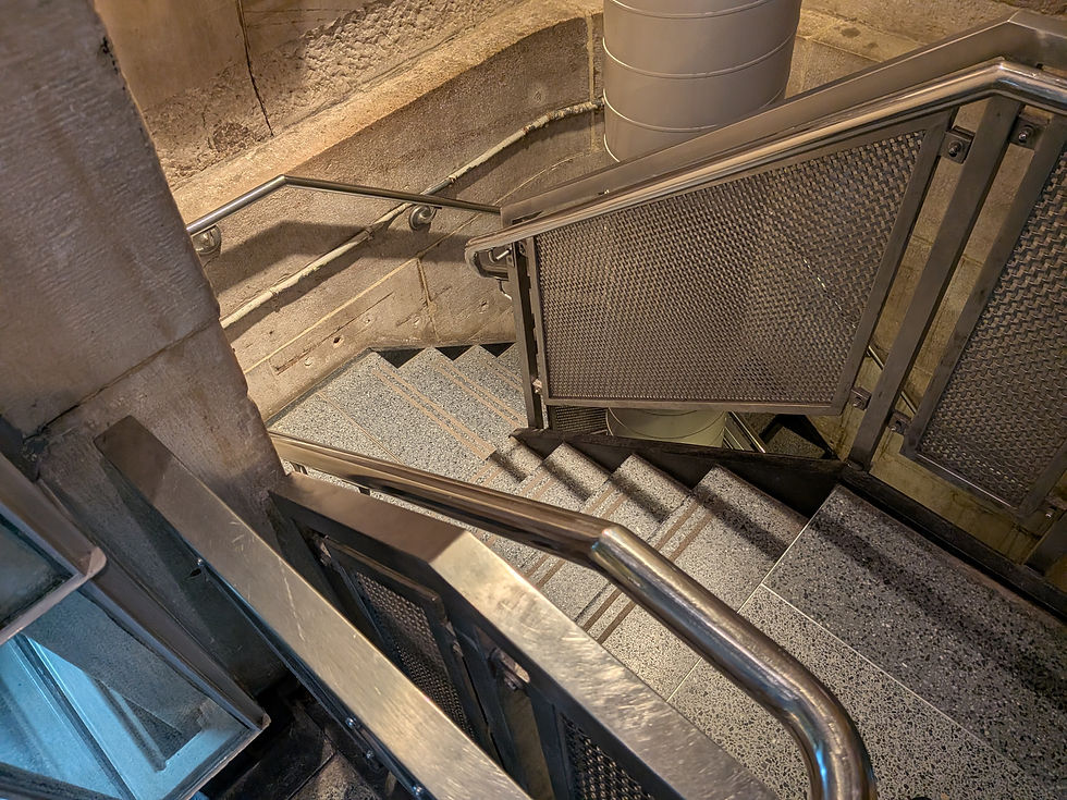 Spiral indoor staircase with metal railings and textured gray steps in a concrete industrial setting, no people visible