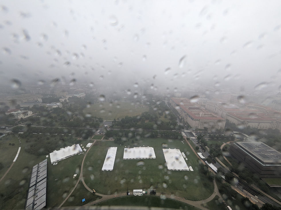 Rainy aerial view of the Great American State Fair grounds and the Ellipse with white event tents and surrounding buildings seen through water-covered glass