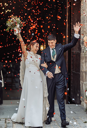 Novios salen de la catedral de Tudela en su boda, entre risas, confeti y lluvia de pétalos. Navarra.