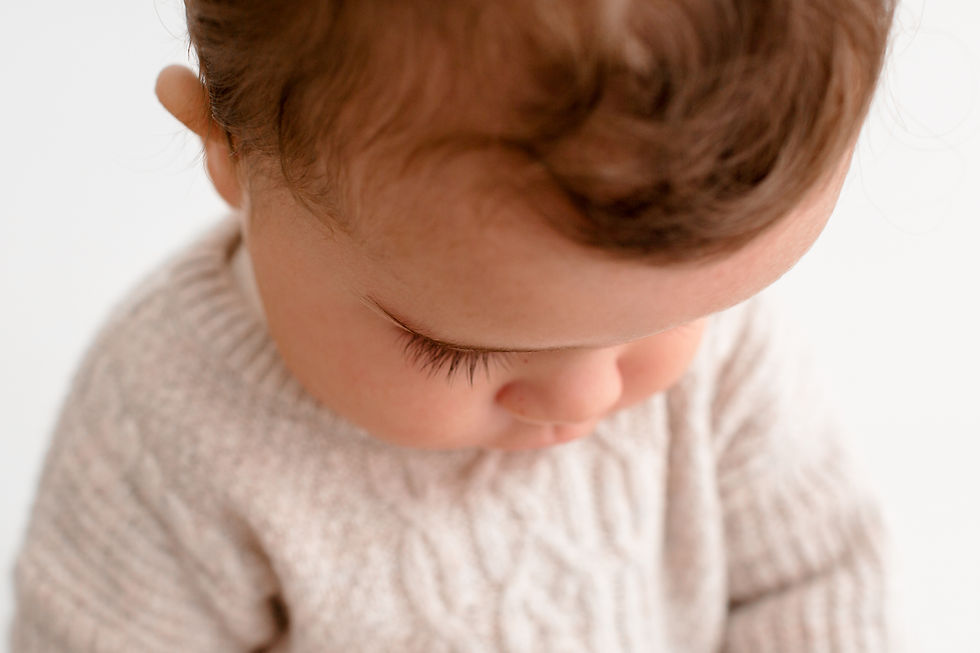 closeup of a baby boy with long lashes looking down at his hands