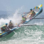 A surf boat tipping going over a wave