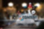 Surrounded by digital icons like rocket, email, clouds. Blurred café background, suggesting creativity.
