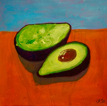 eine aufgeschnittene Avocado auf einem orangenem Tisch vor hellblauem Hintergrund