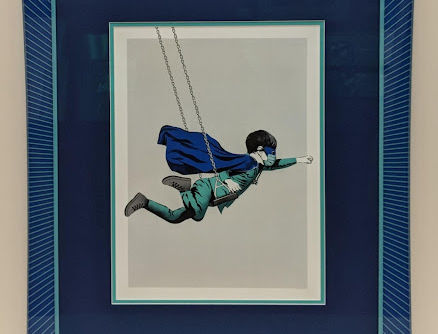Conceptual artwork of a flying figure framed in deep blue layered matting with wide moulding.