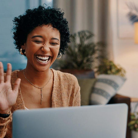 Woman looking at laptop smiling and waving