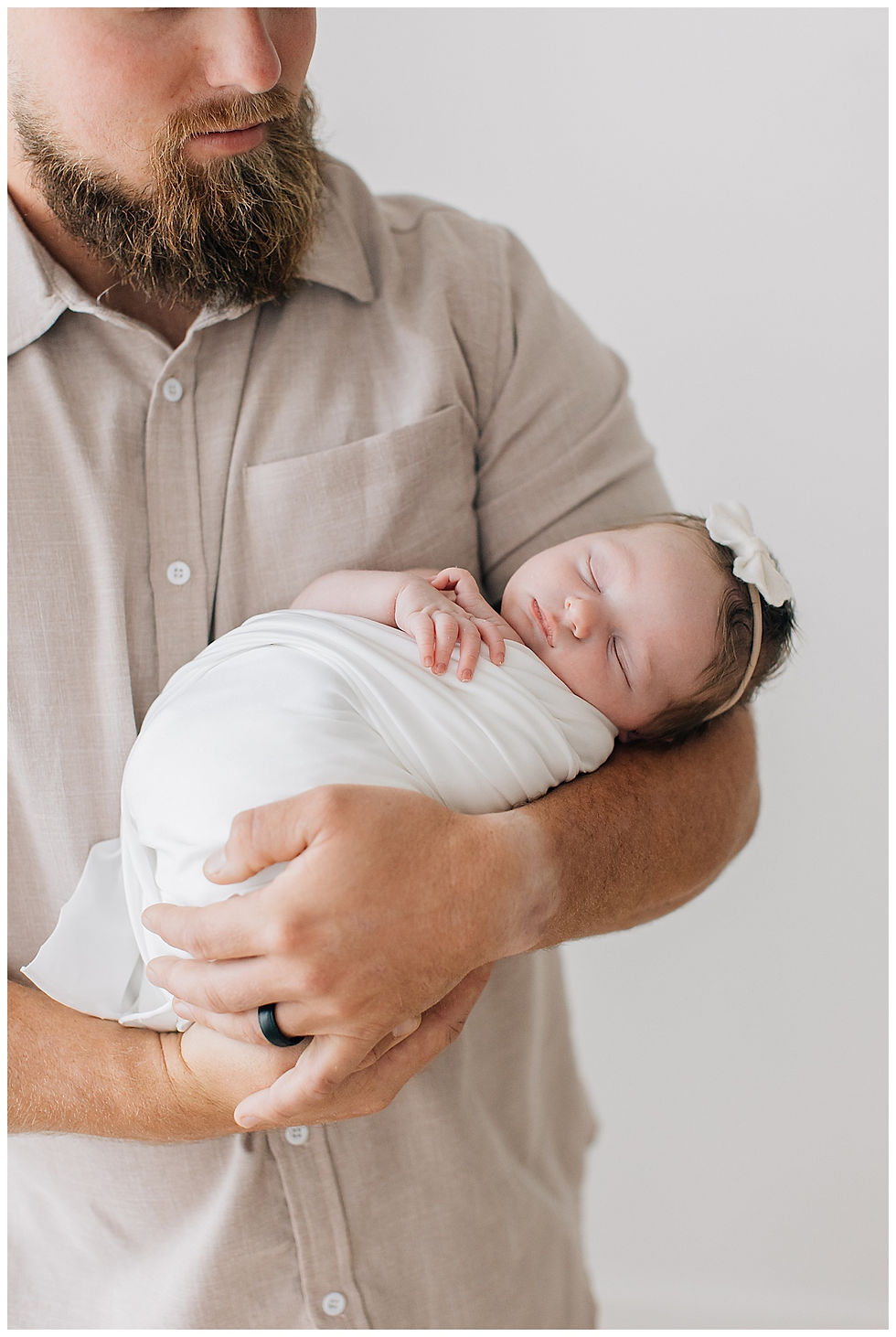 A baby girl in a swaddle being held by her daddy