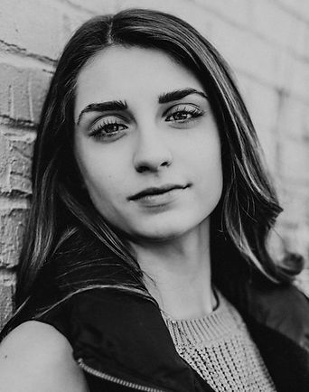 A black and white image of a girl with dark hair staring into the camer
