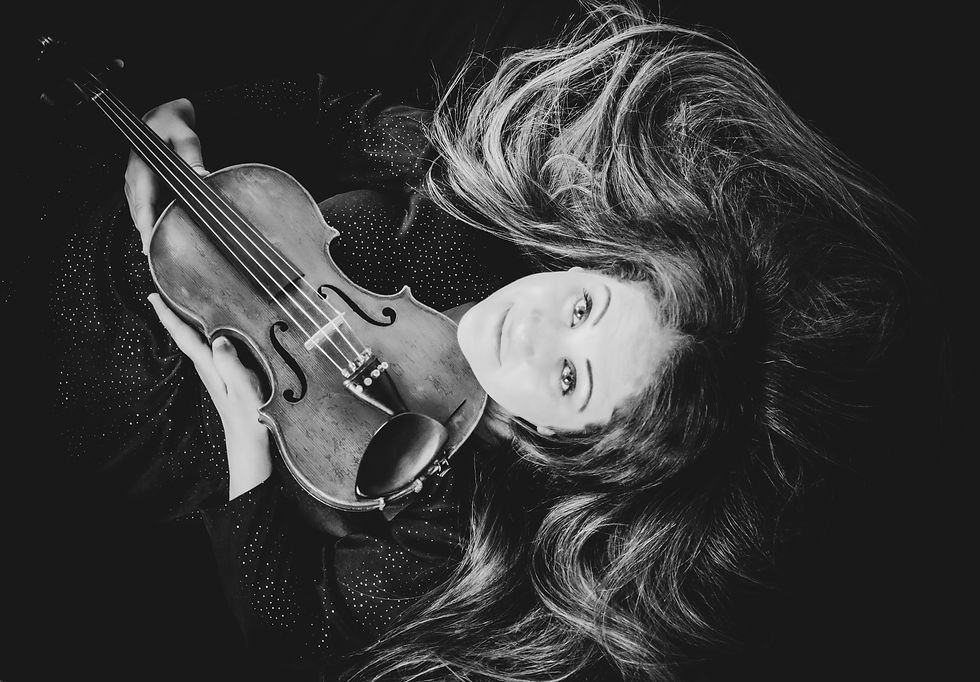 Sarah laying down or sideways with her violin in black and white photo