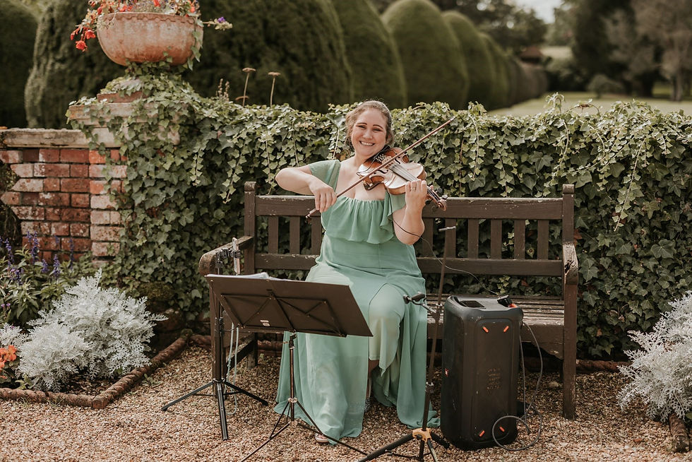 Sarah sitting down in a green dress playing in a garden at a wedding