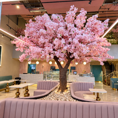 Large artificial pink cherry blossom tree installation with bespoke curved seating in a luxury restaurant interior by SDesign Floral.