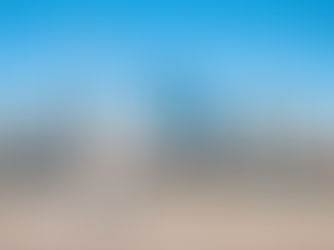 Woman jogging in white outfit along a waterfront with a city skyline in the background on a clear day.