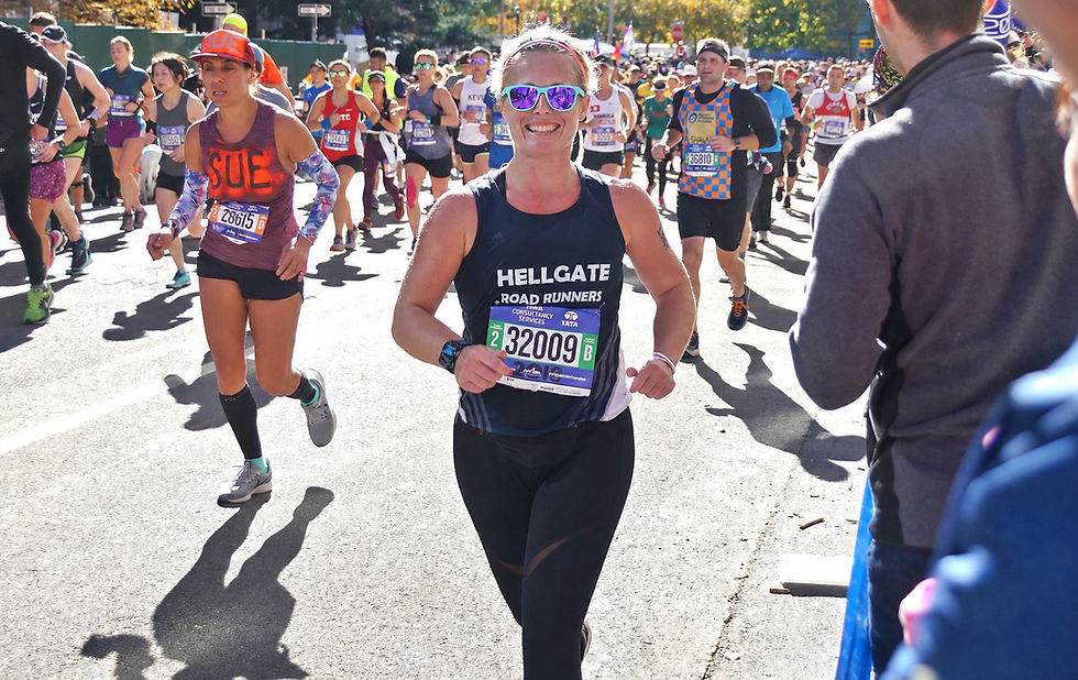 Bonnie Elliot in sunglasses runs in a sunny road race crowd, wearing HELLGATE ROAD RUNNERS bib 32009.