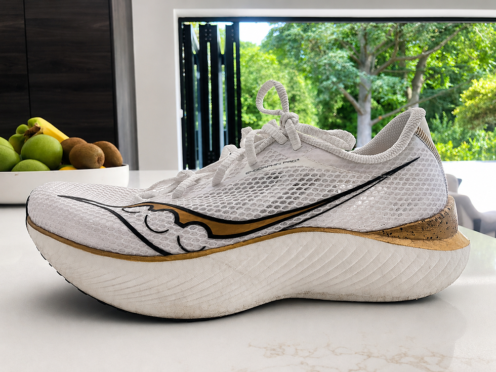 White Saucony Endorphin Pro 3 running shoe on a counter, with fruit bowl and green garden outside a bright window