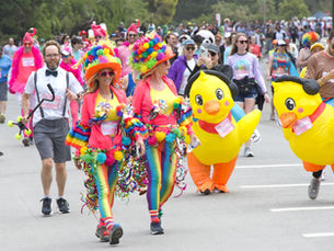 Participants in colourful costumes and inflatable duck suits at Bay to Breakers in San Francisco. Crowd and trees in the background.