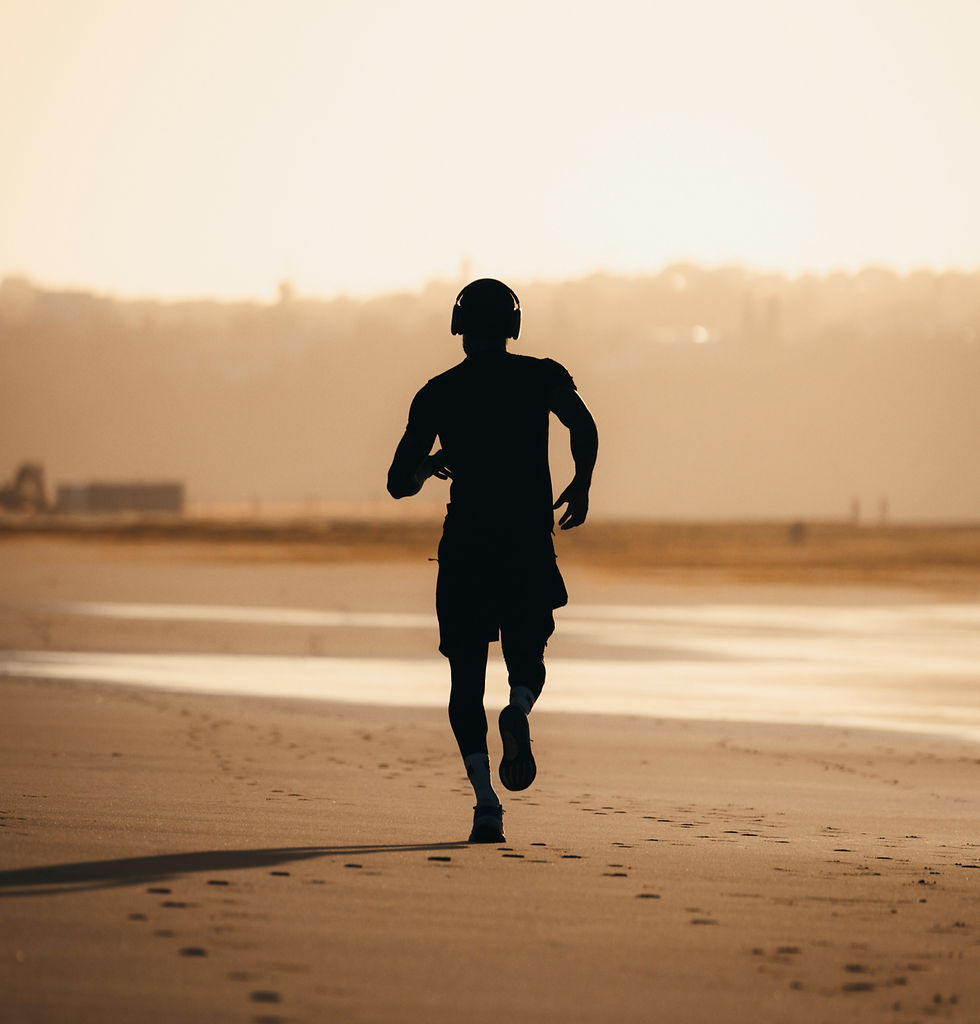  Silhouetted runner wearing headphones runs on a sandy beach at sunset, with warm golden light and footprints behind.