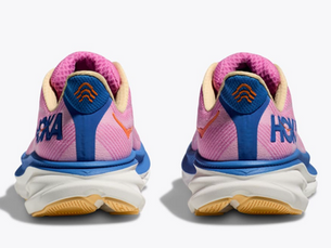 Pink and blue running shoes with orange accents, seen from the back. "HOKA" text on sides. White and yellow soles on a plain background.