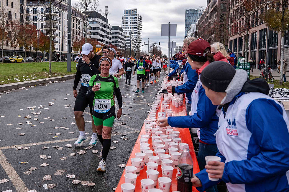 A water station at the Frankfurt Marathon with runners picking up their drinks.