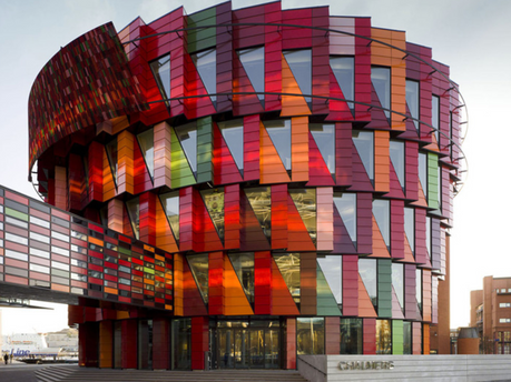 Colourful, multi-story circular building in Gothenburg with red, orange, and green panels. Modern design, urban setting. Chalmers text visible on steps.