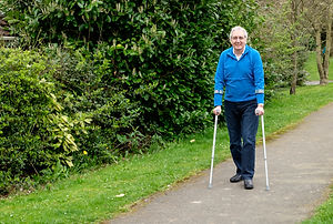 Senior man walking with crutches in park