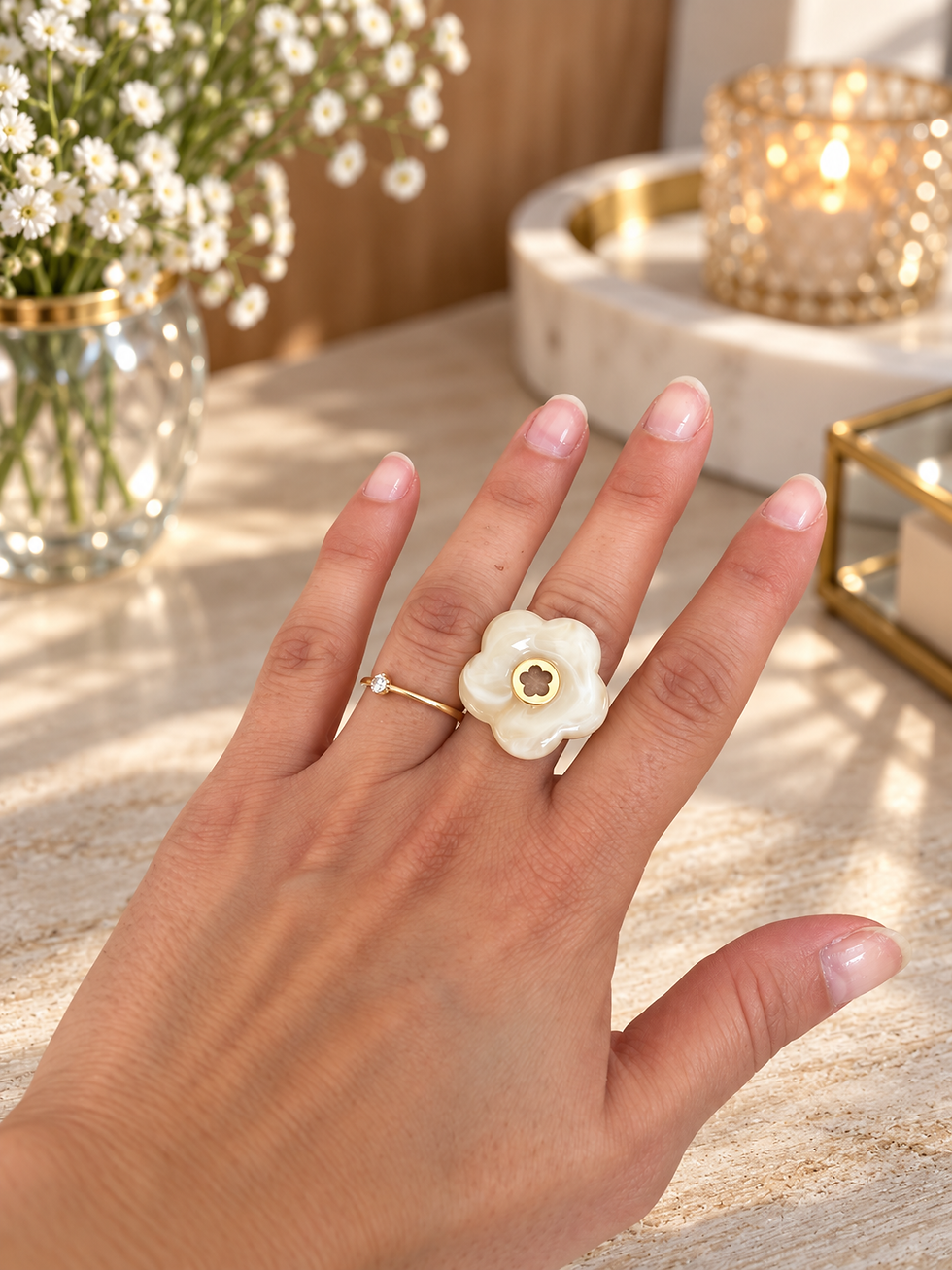 Miniature : Bague Nacréa en acier inoxydable doré, ornée d’une grande fleur blanche aux reflets nacrés et d’un cœur doré, portée à la mai