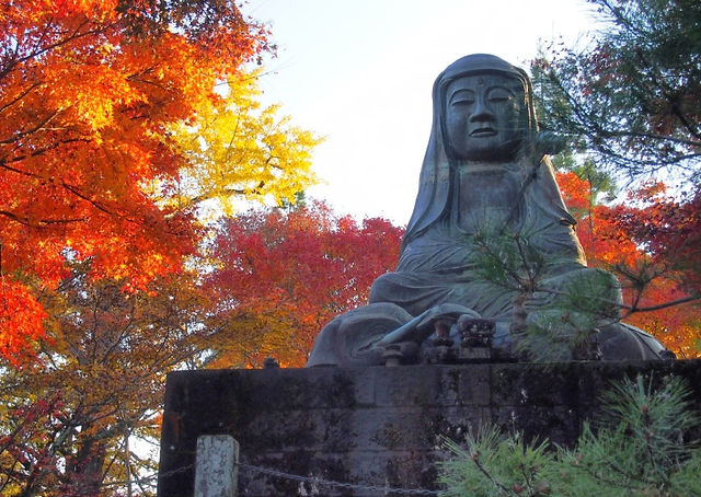 Fugen Bosatsu statue with autumn foliage behind in Usuki