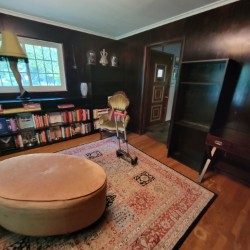 Round ottoman on top of area rug in center of former library 