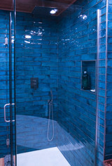 Shower enclosed in blue textured tiles and glass floating door by Barrett Home Renovations