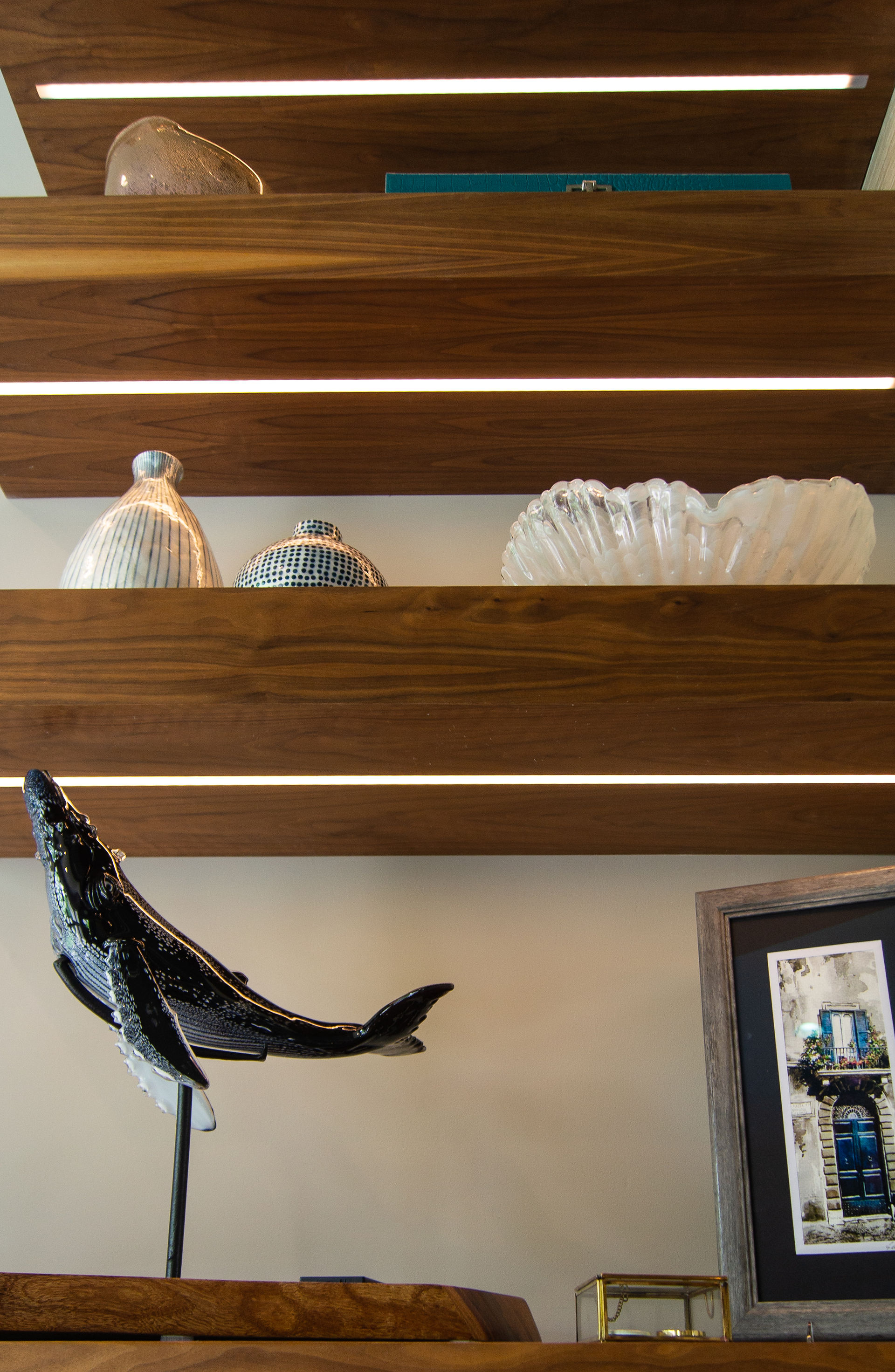 Close up of client's artifacts and art displayed on the stained oak floating cabinet and Floating Shelves Feature by Barrett Home Renovations